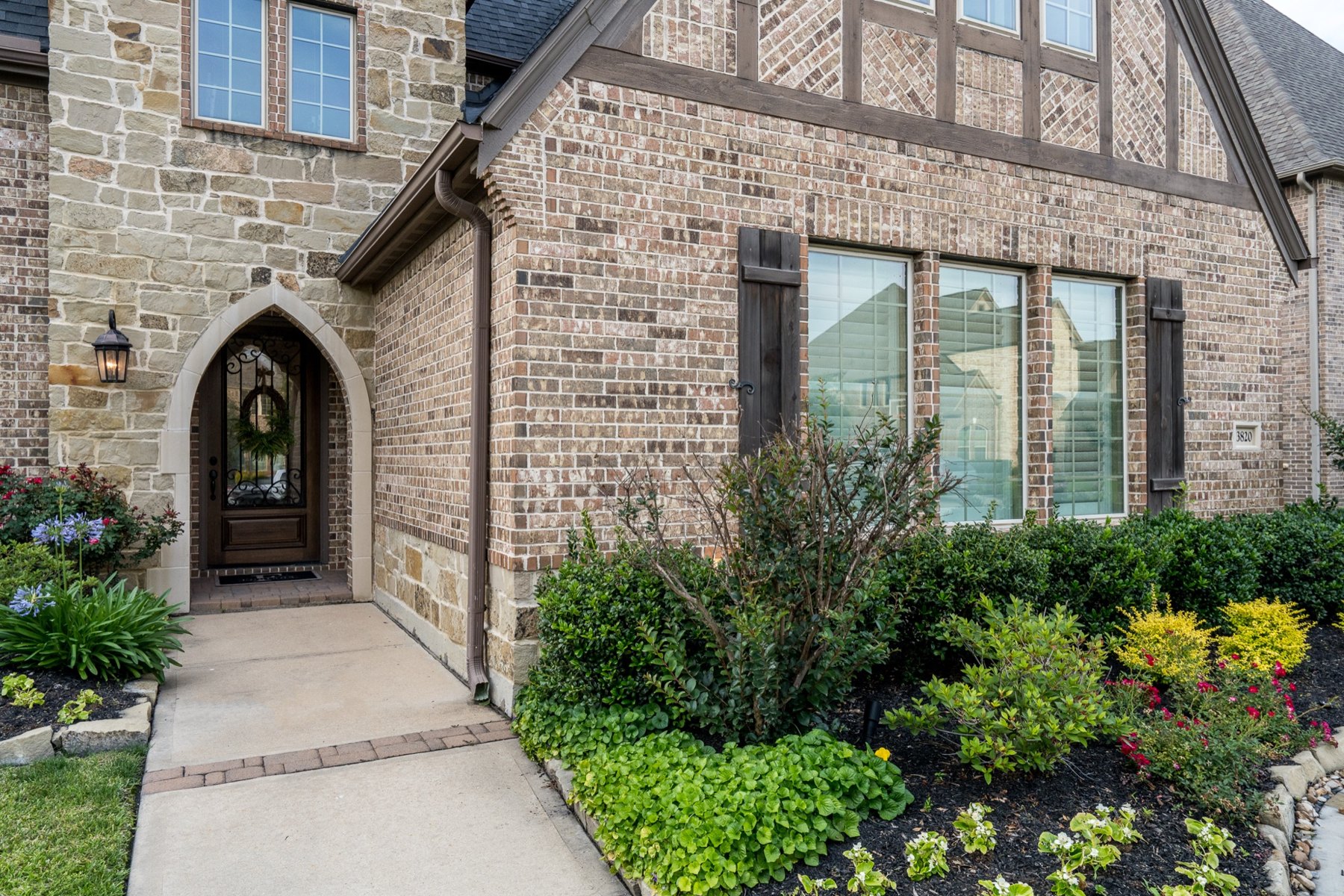 Arched front door framed by planted beds